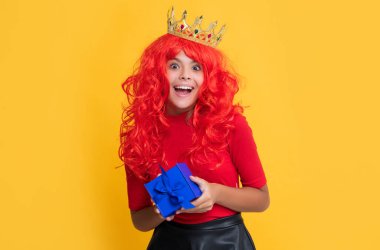 Sarı arka planda hediye kutusu olan tacın içindeki mutlu çocuk. Vay..