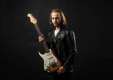 Deri ceketle elektro gitar çalan sakallı rock müzisyeni..