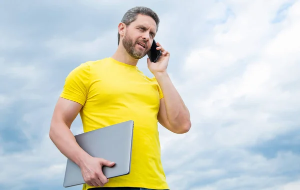 Hombre Con Ordenador Portátil Hablando Teléfono Inteligente Fondo Del Cielo — Foto de Stock