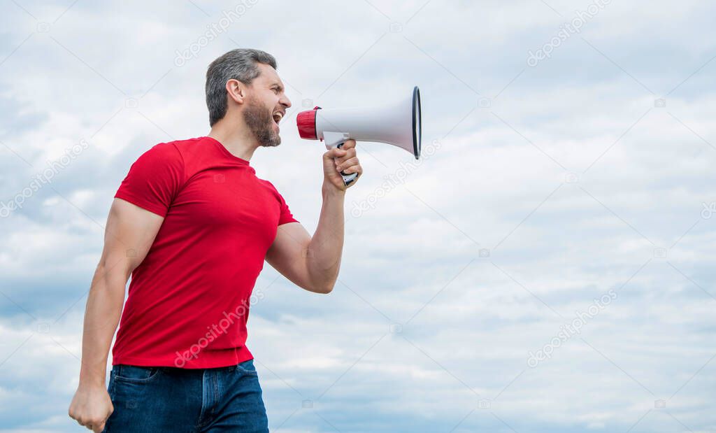 man in red shirt shouting in loudspeaker on sky background.