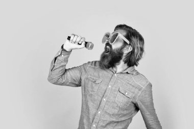 Bıyıklı komik sakallı vahşi adam parti gözlüğü takıyor ve mikrofon ve müzikle şarkı söylüyor..