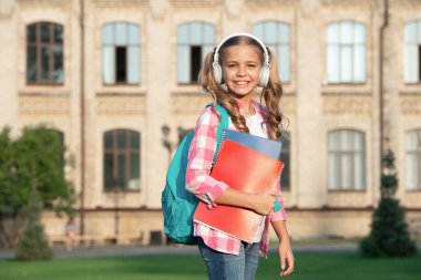 Happy teen girl back to school outdoors, music.
