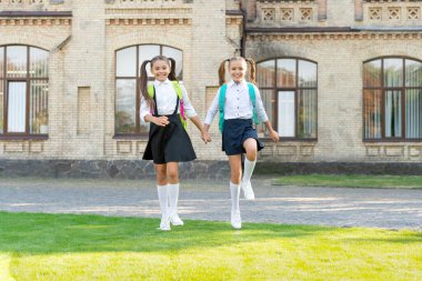 two teen children in uniform walking together outdoor.