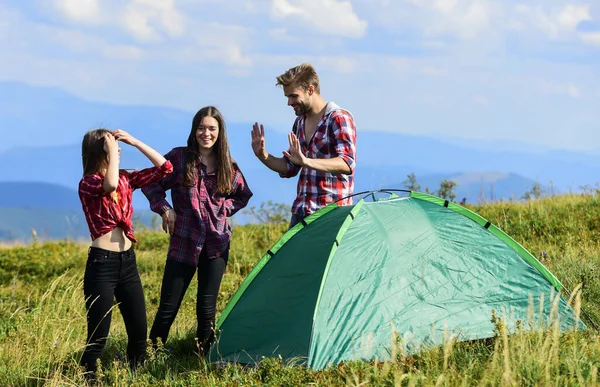 Carefree relax. hiking outdoor adventure. man and two girls pitch tent. wanderlust discovery. mountain tourism camp. group of people spend free time together. friends camping. reach destination place.