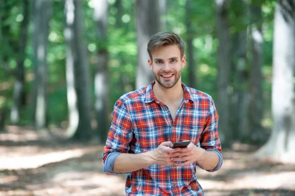 young handsome man in checkered shirt messaging on phone outdoor.