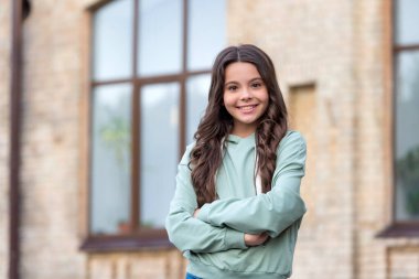 Kendine güvenen genç kız rahat kapüşonlu mutlu kollarını açık havada çapraz tutuyor..