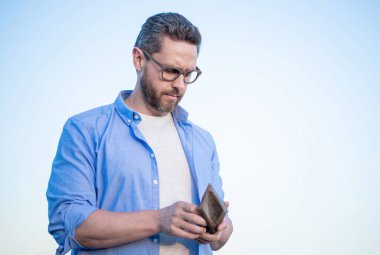 Gözlüklü ciddi bir adam cüzdan açıyor. Arka plan, kopyalama alanı.