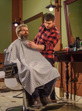 Sakal bakımı. Berber dükkanında olgun bir adam. Kuafördeki vahşi sakallı adam. Erkek müşterisi olan profesyonel berber. Sakallı ve bıyıklı hippi. Adam yeni saç stili istiyor. Erkek güzelliği ve moda.