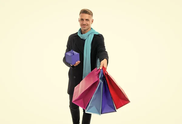 Happy handsome caucasian guy in overcoat with long scarf give paperbags and present gift box isolated on white, shopping.