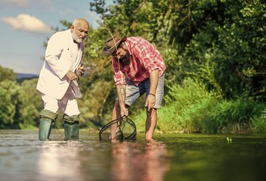 Emekli baba ve olgun sakallı oğul. Yakalama ve balık tutma konsepti. İki erkek arkadaş birlikte balık tutuyor. Mutlu balıkçı arkadaşlığı. İş adamının uçan balık hobisi. emeklilik balıkçılığı. Birlikte eğleniyoruz..