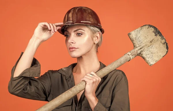 little break. engineer on orange background. foreman girl wear safety hardhat. labor day. woman in boilersuit and helmet. female builder hold shovel. building and construction. lady architect worker.