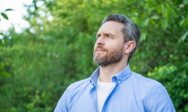 Tıraşsız yakışıklı bir adamın portresi doğal arka plan, kopyalama alanı..