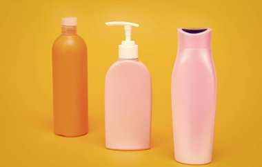 Şampuan, saç kremi ve losyon sıvı tuvalet ürünleri kutuları sıra sarı arka plan fotokopi alanı, şişeler.