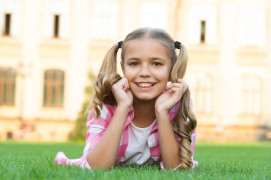 cheerful teen girl portrait relax on green grass outdoor.