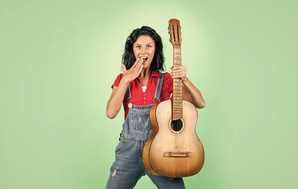 cheerful lady in shirt denim style play the guitar on blue background, music.