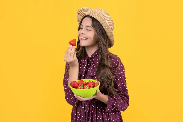 happy teen kid eat strawberry bowl on yellow background.
