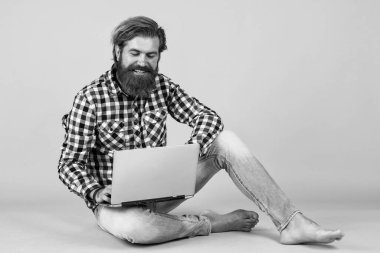 Neşeli hippi bilgisayar kullanıyor. iş dünyasındaki modern teknoloji. Çevik iş. Dijital yaşam tarzı kavramı. Bilgisayarda çalışan olgun bir öğrenci. Adam defter üzerinde çalışıyor. çevrimiçi alışveriş.