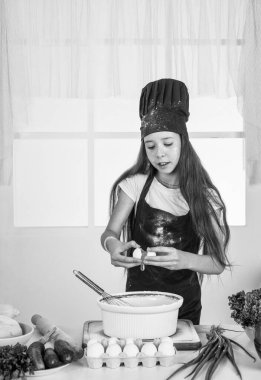 Mutlu çocuk aşçı üniforması giyer. Şapkalı ve önlüklü şef kız. Çocuk mutfakta yemek pişiriyor. Kariyer seçmeyi. Küçük yardımcı pişirme. Mutfak ve mutfak. Mutlu çocukluk. Zevk mükemmellikle buluşur..