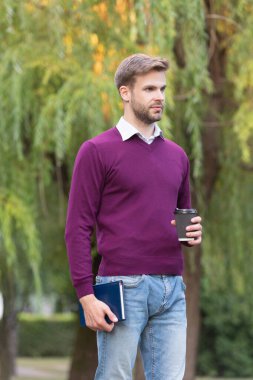 Genç yakışıklı adam sabah kahvesini dışarıda içiyor..