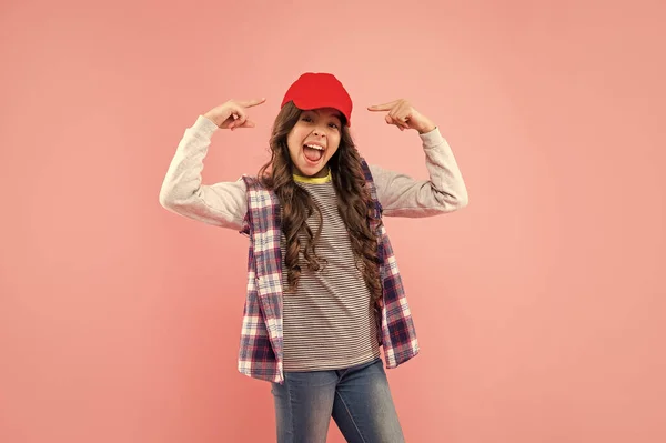 glad kid with curly hair in cap. teen hipster beauty hairstyle. female casual fashion model. frizzy hair curl. girl has wavy hairdo. portrait of frizz child. haircare and skincare. hairdresser.
