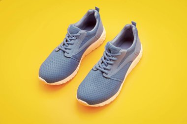 Alışveriş konsepti. Eğitim için ayakkabılar. Koşmak için spor ayakkabıları. Bir çift rahat spor ayakkabı. Spor mavi spor ayakkabılar. Sarı arka planda ayakkabılar. ayakkabı mağazası.