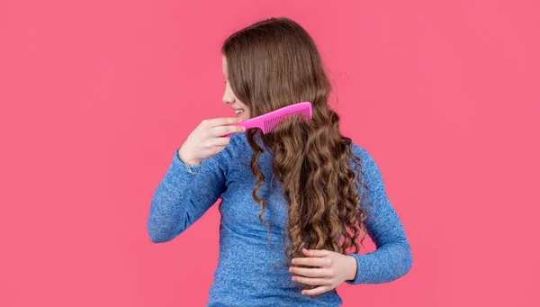 Nastolatek Dziewczyna Czesanie Piękne Kręcone Włosy Szczotką Włosów Różowym Tle — Zdjęcie stockowe