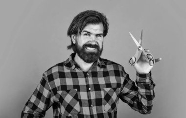 Bıyıklı ve sakallı yakışıklı hippi. Makas, berber dükkanı gibi kuaför aletleri kullanıyor..