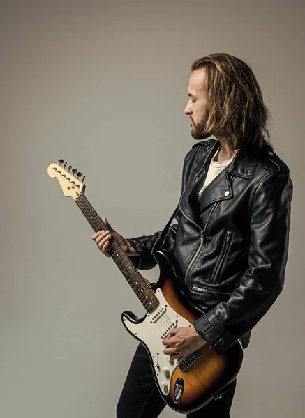 bearded rock musician playing electric guitar in leather jacket, rock music.