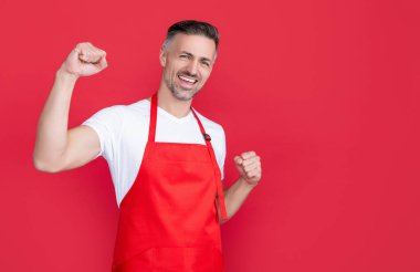 mature barman in apron on red background.