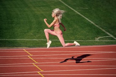 sport woman in sportswear sprinting on stadium running track before training fitness, active lifestyle.