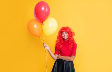 Sarı arka planda parti balonuyla gülümseyen genç kız..