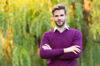 Gündelik tarzda giyinen yakışıklı genç adam dışarıda ellerini çapraz yaptı. Boşluğu kopyala.