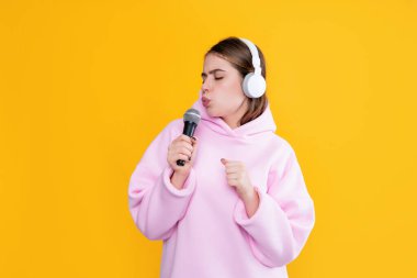 Sarı arka planda mikrofonu olan kulaklıklı komik bir genç kız..