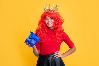 Sarı arka planda mevcut kutusuyla taç giymiş gülümseyen kız..