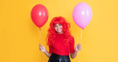 Sarı arka planda parti balonu olan neşeli genç çocuk..