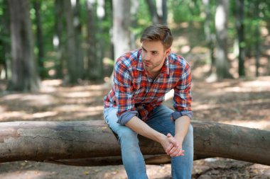 Kareli tişörtlü, açık havada dinlenen genç yakışıklı adam..