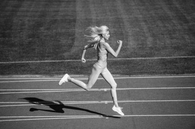 Hareket halindeki kadın. Atletik bayan sprint 'te yarışıyor. Spor, sağlıklı yaşam tarzı. Spor salonu açık havada. Koşucu pistte hızlı koşar. Enerjik ve sportif. maraton hız enerjisi.