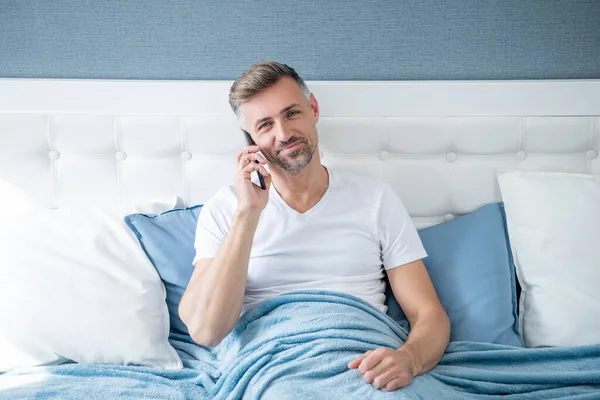 Mature Man Smile Bed Speaking Phone — Stockfoto