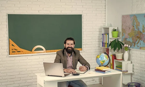 Explore something new. pass the exam. learning the subject. happy man with beard work on computer. studying online. informal education. male student sit in school classroom on lesson with blackboard.