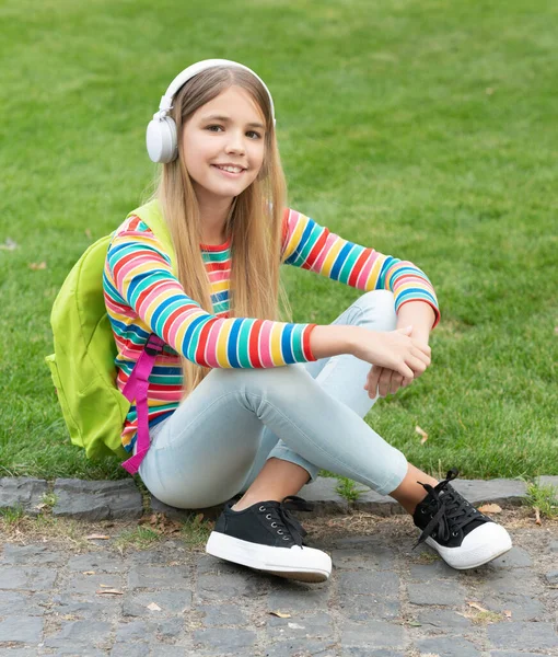 Happy Tween Girl School Backpack Listening Music Sitting Grass Outdoors — Fotografia de Stock