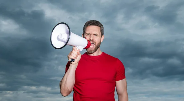 man in red shirt shout loud in loudspeaker on sky background.