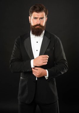 bearded bridegroom in tuxedo on black background, formalwear.