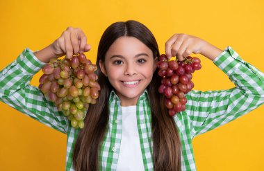 Sarı arka planda üzümlü pozitif çocuk.