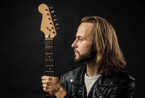 guitar neck. man long hair hold electric guitar fingerboard. rock music style. musician guitar player. stylish crazy man. six string musical instrument. bearded rocker in leather jacket.