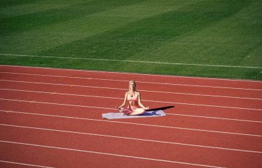 Formda bayan spor sonrası stadyumda meditasyon yapıyor, yoga yapıyor..