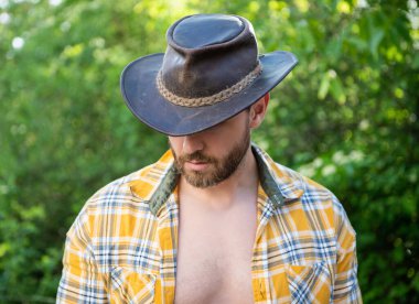 man in cowboy hat look down. sexy cowboy in checkered shirt. western cowboy wearing hat.