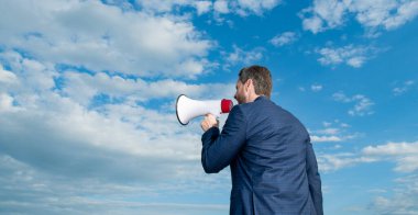 back view of businessman shout in loudspeaker on sky background. copy space.