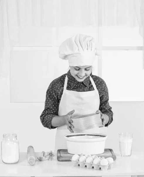 Look whats cooking. happy teen girl cooking dough. kid in chef uniform. culinary and cuisine. child in cook hat and apron. baker baking at kitchen. healthy food. homemade pastry. happy childhood.