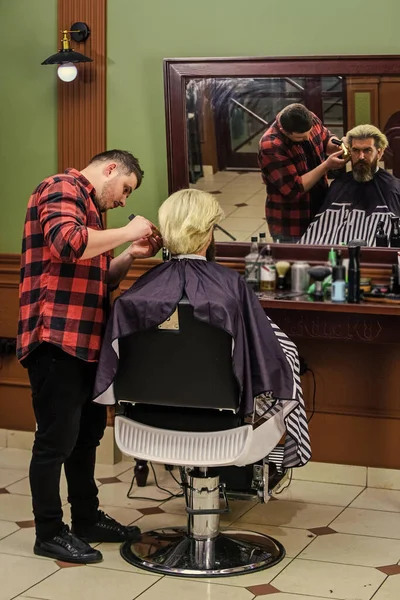 brutal bearded man at hairdresser salon with master, hair style.