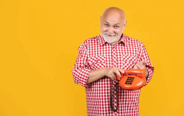 positive aged man with retro telephone on yellow background.